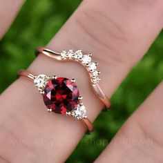 a woman's hand with a ring on it and a red stone in the middle