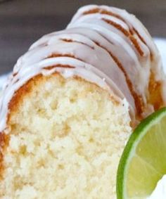 a piece of cake with frosting and a lime slice on the plate next to it