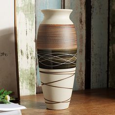 a white vase sitting on top of a wooden table