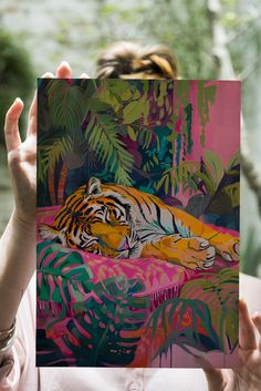 a woman holding up a painting with a tiger on it