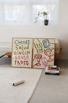 two framed art pieces sitting on top of a white rug