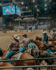 several men riding horses in an arena at a rodeo