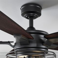 a ceiling fan with wooden blades and a caged light fixture hanging from the ceiling