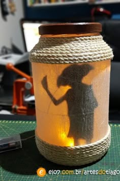 a mason jar with a shadow of a woman on it and rope wrapped around the lid