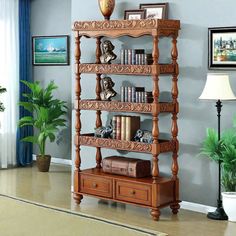 a wooden book shelf with many books on top of it in a living room next to a potted plant