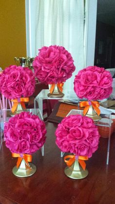 four vases filled with pink flowers on top of a wooden table