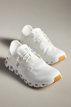 white sneakers with orange soles are on a gray surface