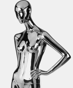 a shiny silver female mannequin standing on one leg and holding her hands behind her back