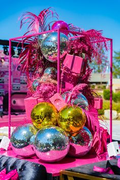 a pink table topped with lots of shiny balls and disco balls on top of it