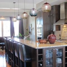 a kitchen with marble counter tops and black chairs in front of an island that has wine glasses on it