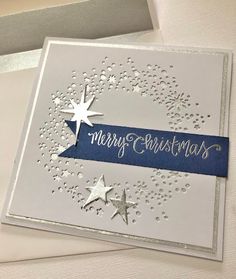 a white card with silver stars and blue ribbon on it that says merry christmas in the middle