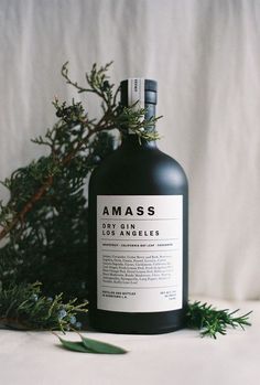 a bottle of liquid sitting on top of a table next to some plants and leaves