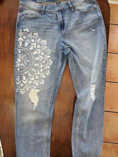 an old pair of jeans that have been painted with white designs on them, sitting on a wooden table