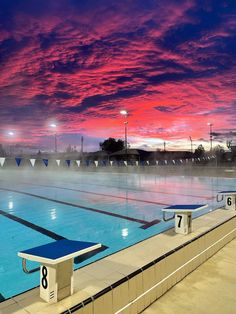 an empty swimming pool with the sun setting in the background