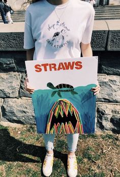 a girl holding up a sign with the words straws on it and a drawing of a sea turtle