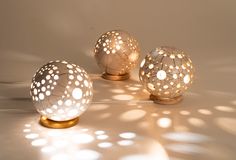 three decorative glass balls sitting next to each other on a white surface with light shining through them