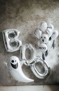 balloons are arranged in the shape of numbers and ghost faces on a concrete wall,