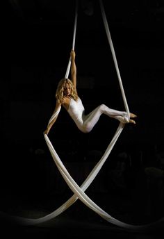 a woman in white shirt and tight pants on aerial acrobatics