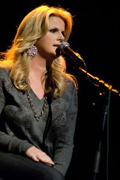 a woman sitting in front of a microphone on top of a stage next to a keyboard