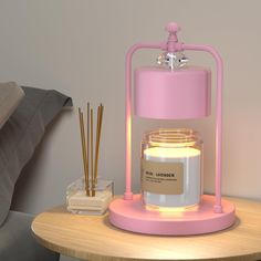 a pink candle sitting on top of a wooden table next to a glass jar filled with candles