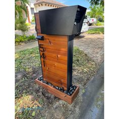 a wooden box with letters on it sitting in the middle of a yard next to a tree