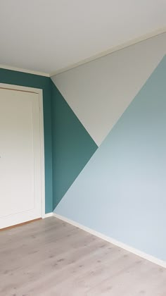 an empty room with blue and white paint on the walls, wood floors and a door