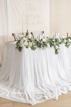 the table is set up with white flowers and greenery for an elegant wedding reception