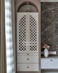 a white cabinet sitting next to a window in a room with marble walls and flooring