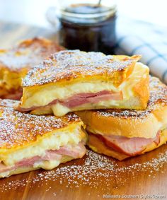 ham and cheese sandwich cut in half on a wooden cutting board with powdered sugar