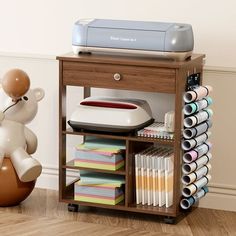 a teddy bear sitting on top of a ball next to a printer and other craft supplies