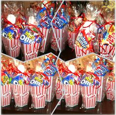 red and white striped popcorn buckets with candy on sticks tied to the top, wrapped in cellophane