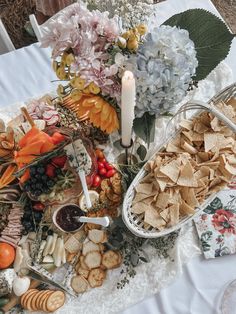 a table topped with lots of different types of food next to a candle and flowers