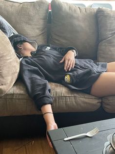 a woman laying on top of a couch next to a table with a knife and fork