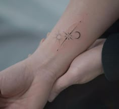 a person holding their hand with a small tattoo on it