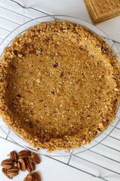 a pie sitting on top of a cooling rack next to pecans and crackers