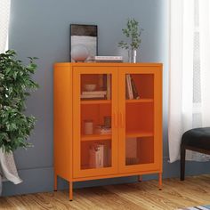 an orange bookcase in the corner of a room next to a potted plant