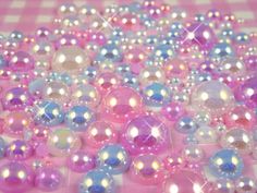 many different colored beads on a pink and white checkered tablecloth with sparkles