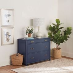 a blue dresser in a white room with potted plants on top and other decor