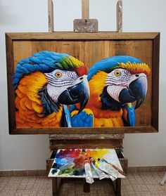 two colorful parrots are on display in front of an easel