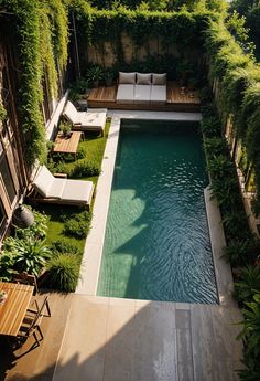 an outdoor swimming pool surrounded by greenery and wooden lounge chairs with cushions on them