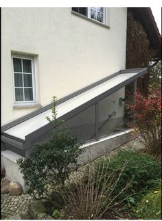 a cat sitting on the side of a window sill in front of a house