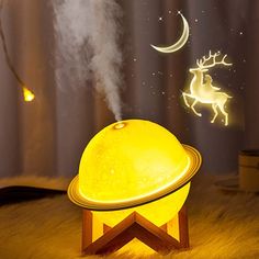 a night light that is on top of a table with a deer and moon in the sky above it