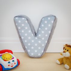 a stuffed animal sitting next to a toy phone and letter v on the wall in a child's room