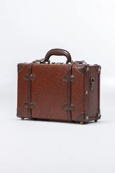 a brown leather suitcase sitting on top of a white floor next to a wooden handle