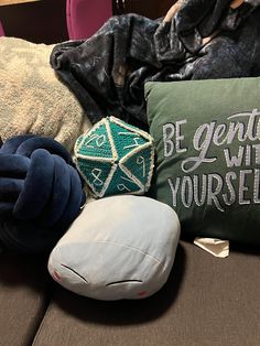 pillows, blankets and stuffed animals are sitting on a couch with the words be gentle with yourself printed on them