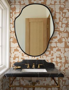 a bathroom with a sink, mirror and wallpaper in the shape of animals on it