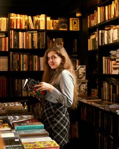 a woman standing in front of a book shelf filled with books