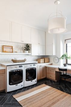 a kitchen with white cabinets and black flooring next to a washer and dryer