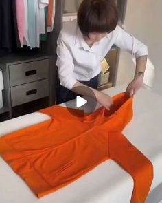 a woman is cutting an orange shirt with scissors