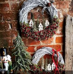 two wreaths are hanging on a brick wall next to christmas trees and other decorations